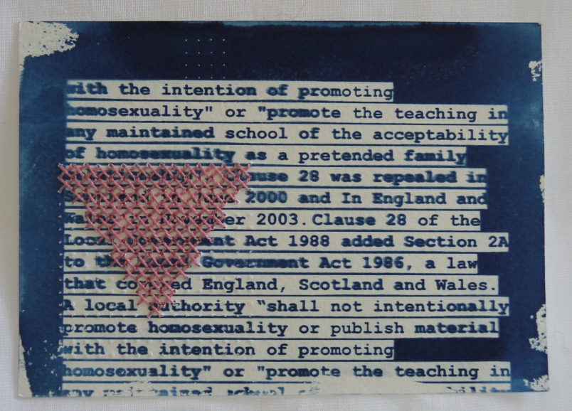 Title: Section 28 A postcard with text printed in deep blue, with an unevenly brush-applied deep blue border. Pink stitches on the left are arranged in a triangle, point facing downwards. The text relates to Section 28, reading "with the intention of promoting homosexuality" or "promote the teaching in any maintained school of the acceptability of homosexualty as a pretended family... clause 28 was repealed in.... 2000 and in England and Wales.... 2003. Clause 28 of the Local Government Act 1988 addded Section 2A to the Local Government Act 1986, a law that covered England, Scotland and Wales. A local authority "shall not intentionally promote homosexuality or publish material with the intention of promoting..."